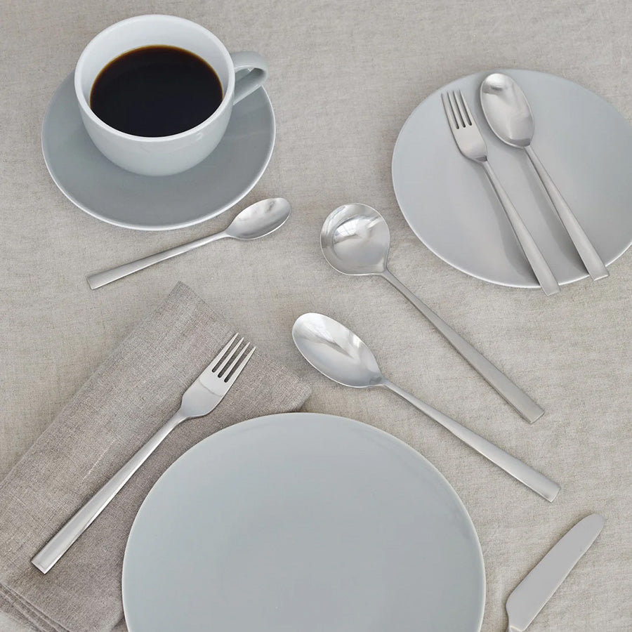 Elegant borddekk med Stelton Chaco dessertskje, dessertgaffel, tallerkener, kopper og bestikk i rustfritt stål, ideelt for en stilfull dessertopplevelse.