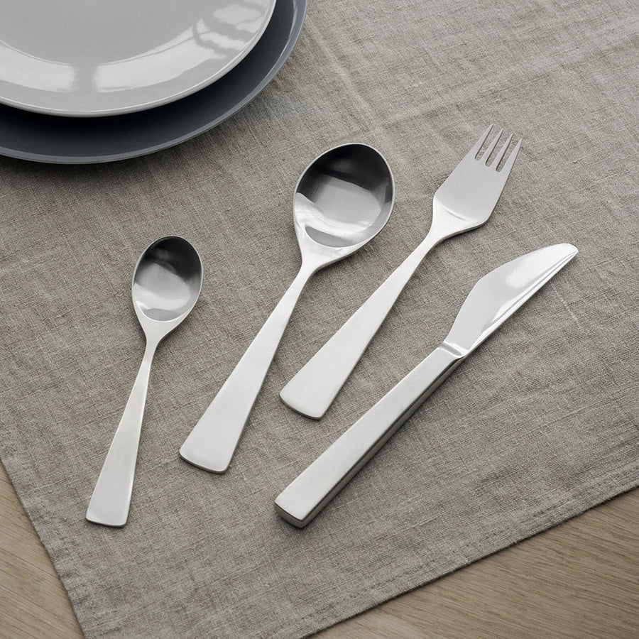 Stelton Maya bestikksett som inkluderer teskje, gaffel, skje og kniv på en elegant duk.