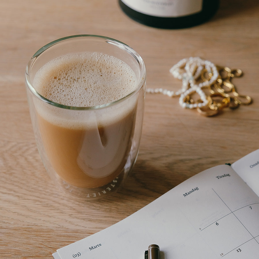 Teministeriet glass med kaffe på et skrivebord, utformet for en stilren og varm drikke.