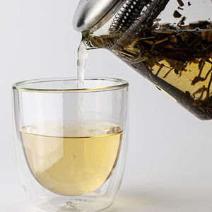 Te helles fra Teministeriet tekanne inn i et glass, med utrekking av teblader synlig.