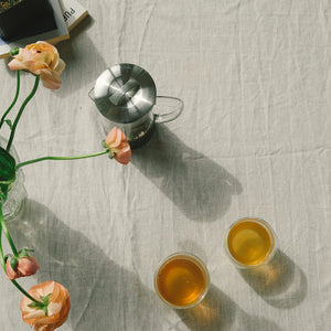 Overhead bilde av Teministeriet glass tekanne på et bord med to kopper te og blomster, perfekt for en koselig stund.