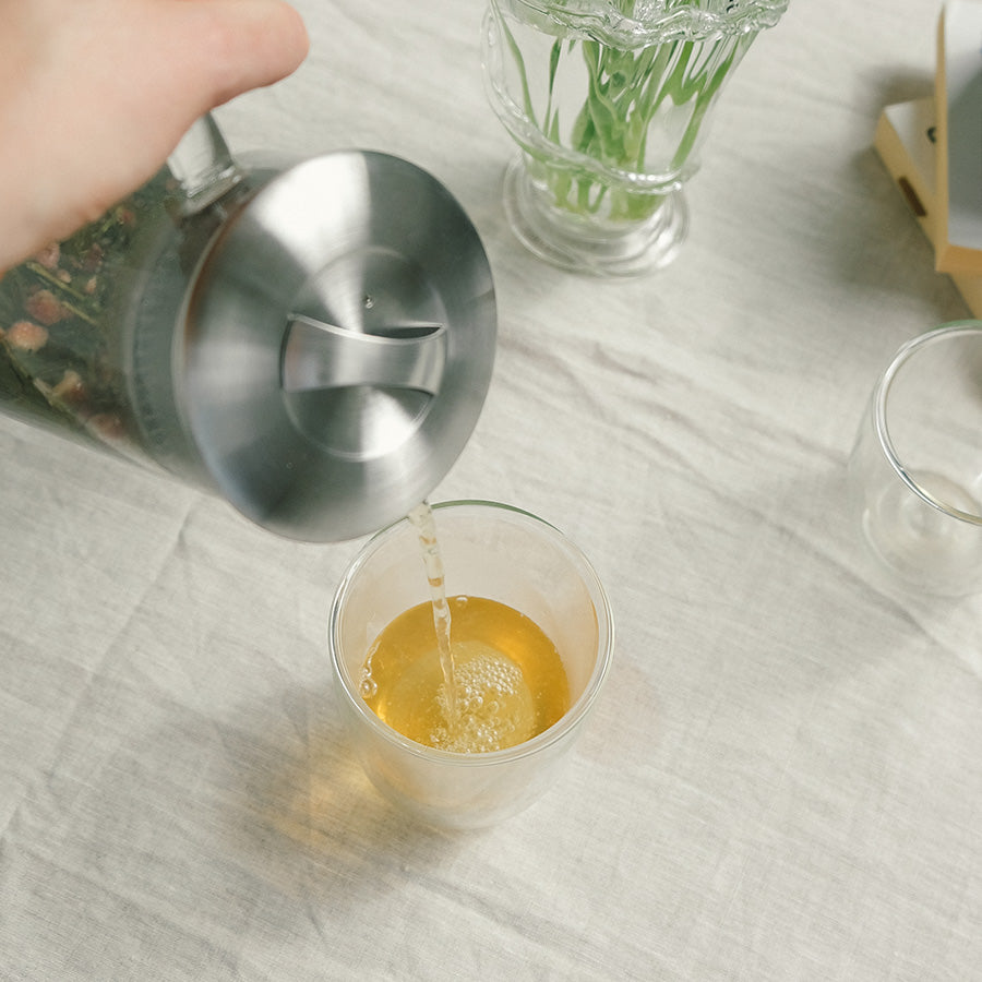 En hånd som heller Teministeriet Moomin Rooibos Red Berries Te fra en tekanne til et glass.