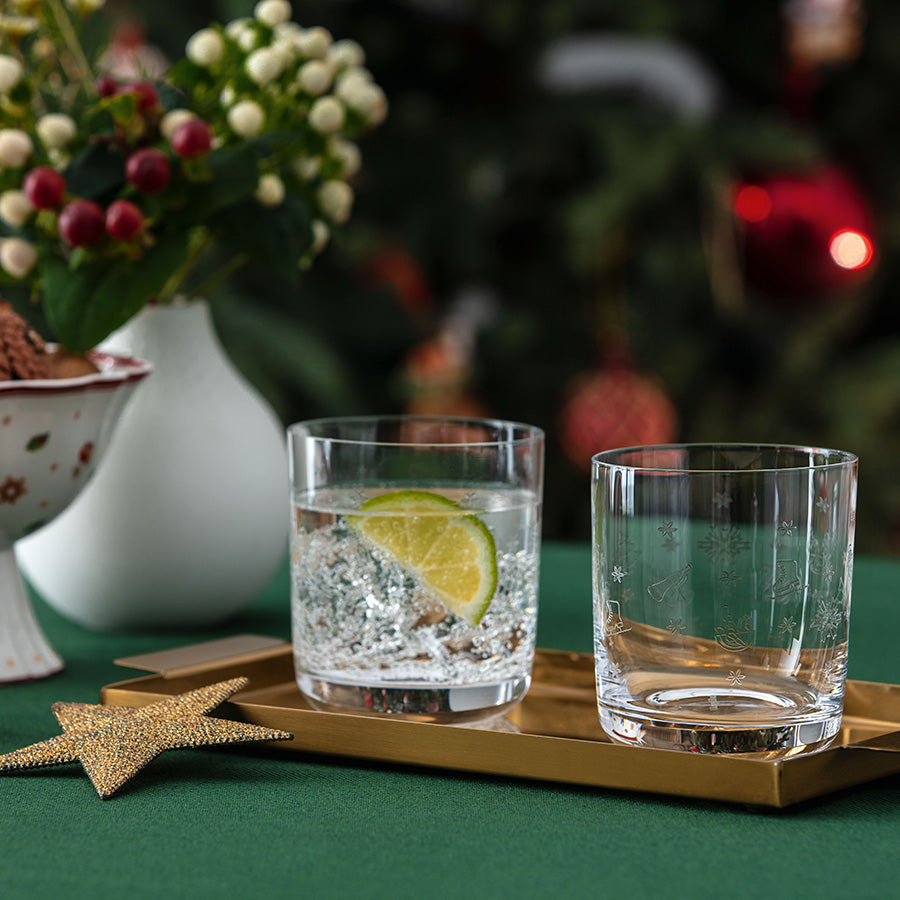 Toy's Delight vannglass med vann og lime, samt et tomt glass på julepyntet bord