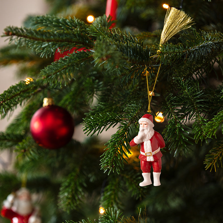 Julenisse-ornament fra Villeroy & Boch henger på et pyntet juletre med julelys og røde kuler