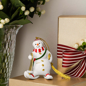 Villeroy & Boch snømann-ornament 2026 står som juledekorasjon ved gave og vintergrønne kvister