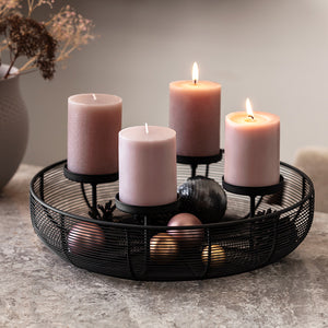 Rund svart adventsstake med fire rosa kubbelys og juledekorasjoner på bordet