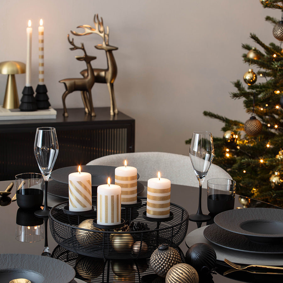 Rund adventsstake med tente kubbelys på julebord med juletre og julepynt