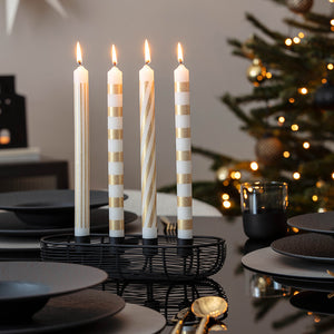 Elegant adventsstake med fire tente kronelys på julepyntet spisebord
