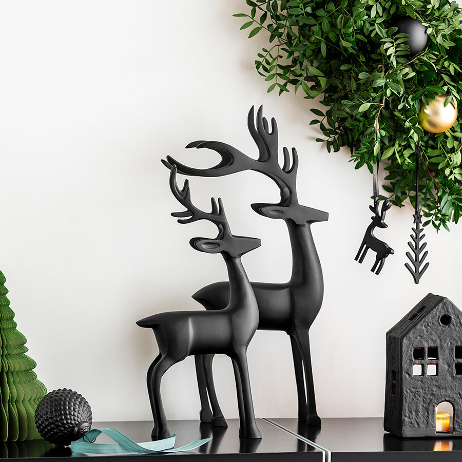 Sort glasskule med relieffmønster og grønt bånd som julepynt i elegant vinterdekor