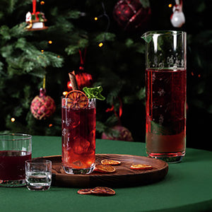Toy's Delight glassmugge med rød julepunsj ved siden av serveringsglass og julepynt