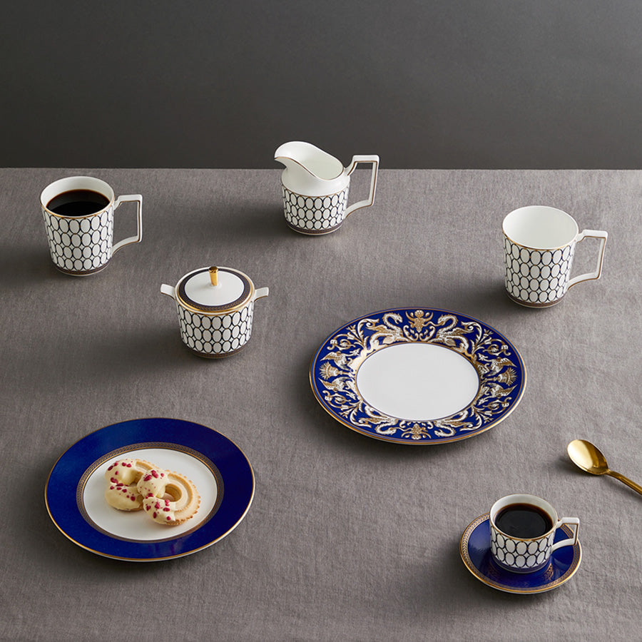 Samlet borddekorasjon med Wedgwood Renaissance Gold Fløtemugge 20cl, inkludert kopper og tallerkener i blått og gull.