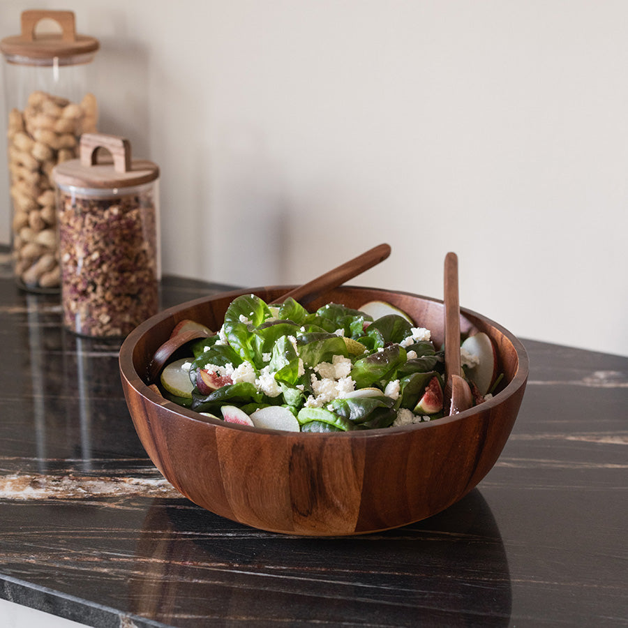 Christiania 1739 salatbolle fylt med frisk salat og akasietre bestikk, plassert på en elegant benk.