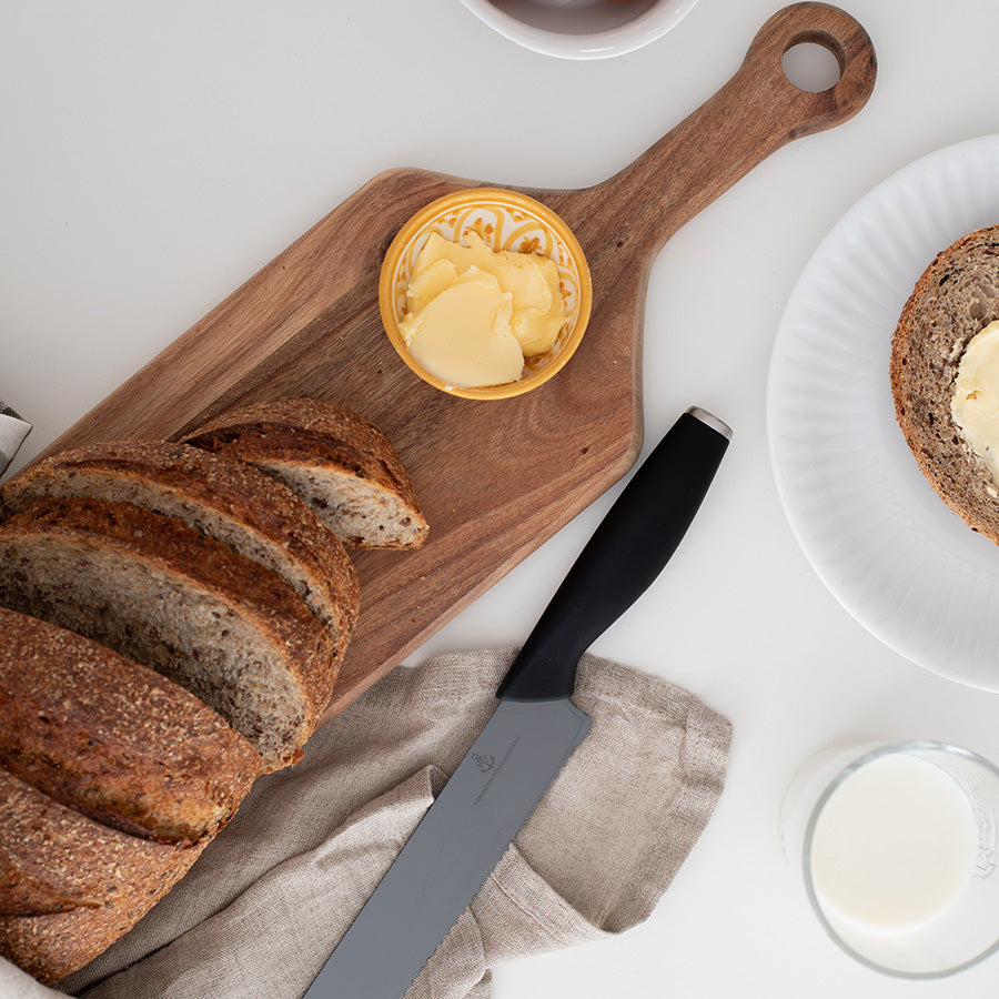 Brød skåret på trefjøl med smør, ideell for servering og matlaging.