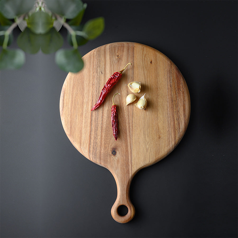 Rund trefjøl av akasie med dried chili og hvitløk på, ideell for matlaging og som serveringsbrett.