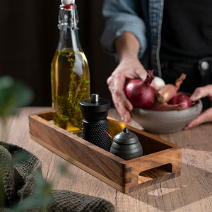 Bruk av serveringsbrett i akasietre med olivenolje, krydderkverner og en bolle med grønnsaker, perfekt til borddekking.