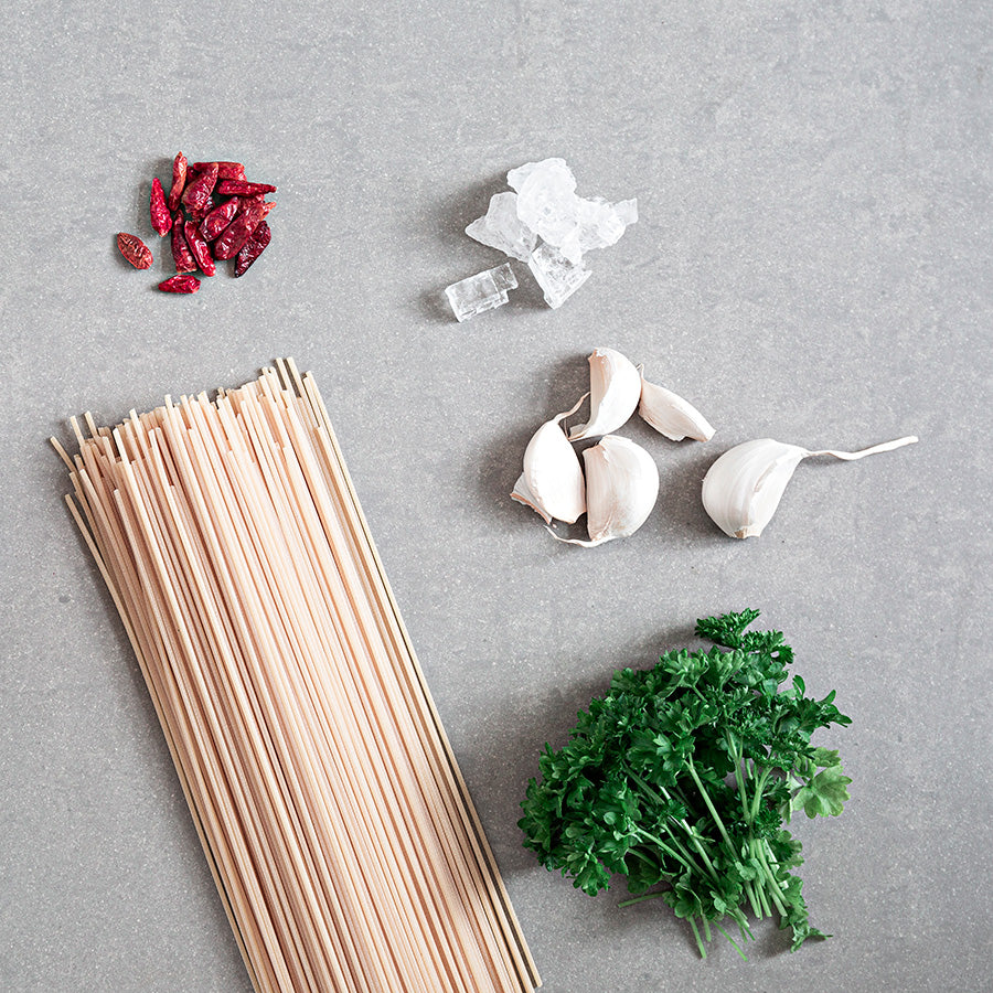Ingredienser til en pastarett med Adelante Pasta Salt, inkludert spaghetti, hvitløk, tørket chili, persille og halittsalt - alt du trenger for en smakfull middag.