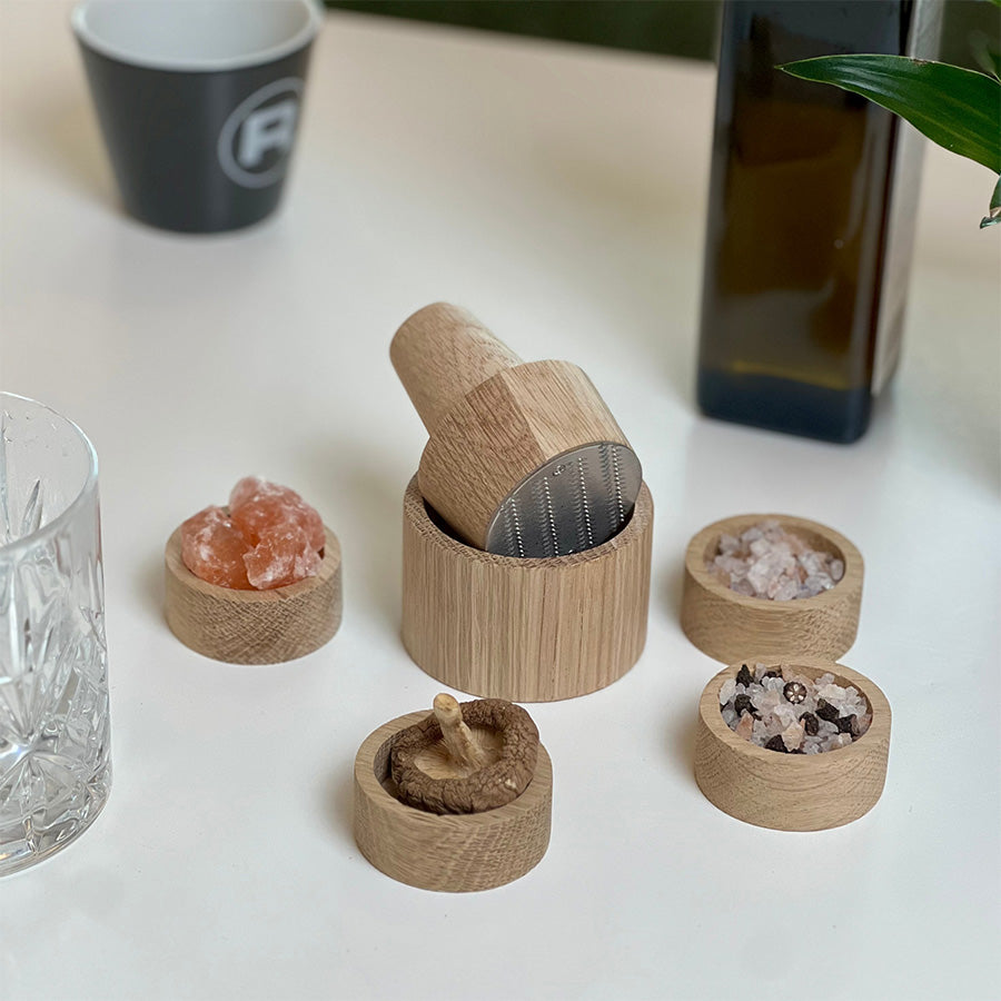Eik skåler fra RIVSALT med forskjellige krydder og minikvern, en stilren krydderstasjon for bordservering.