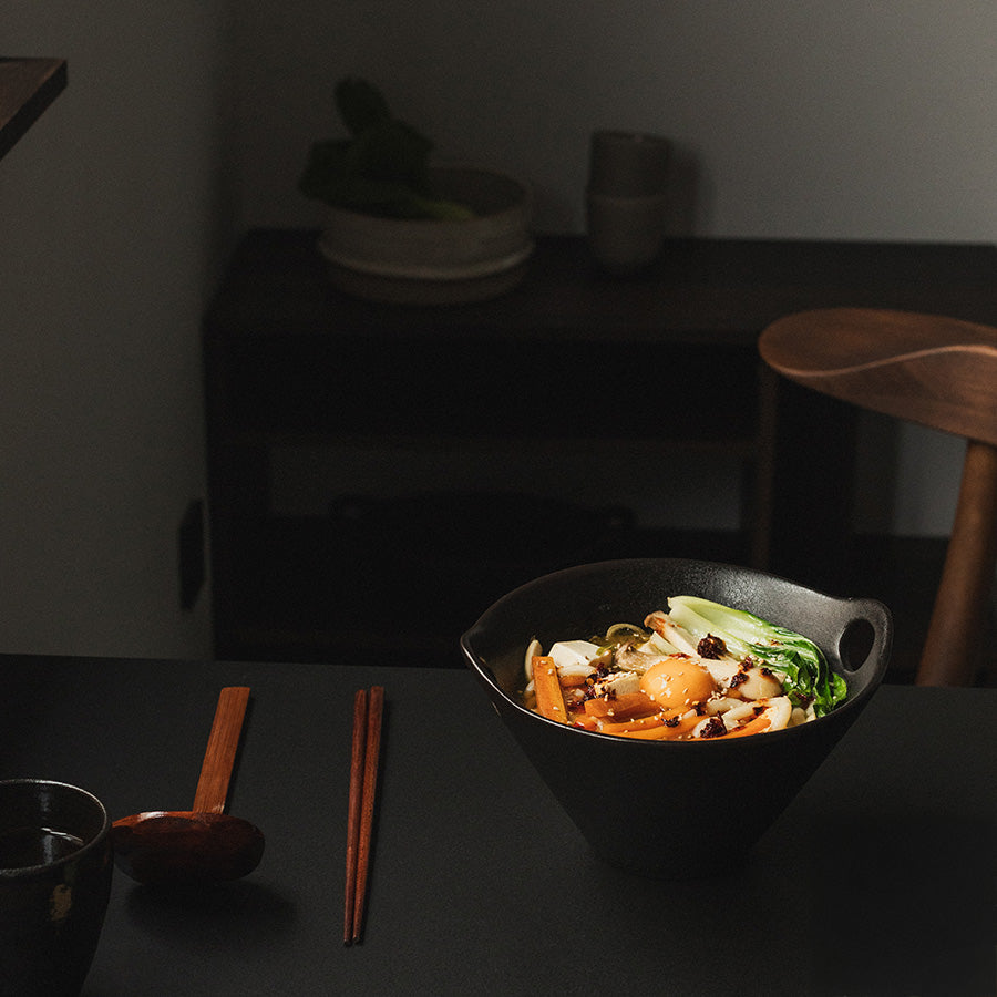 Ramenbolle fylt med deilige grønnsaker, sammen med spisepinner og skje, perfekt for asiatisk mat.