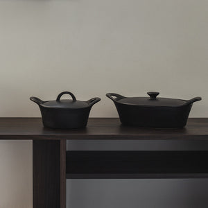 To sorte ildfaste former, en stor oval og en liten rund på en hylle, flott for dekor og oppbevaring.