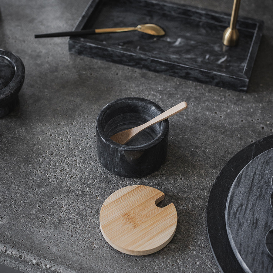 Stilig oppbevaringskrukke i grå marmor plassert på et moderne betongbord med en treskje, detaljert interiør.
