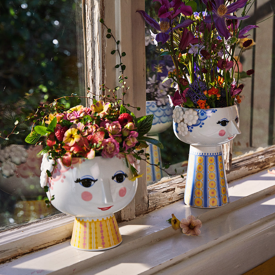 To Bjørn Wiinblad potteskjulere med blomster i vinduskarmen, med kunstneriske ansiktsdesign og lyse farger, ideal for innredning.