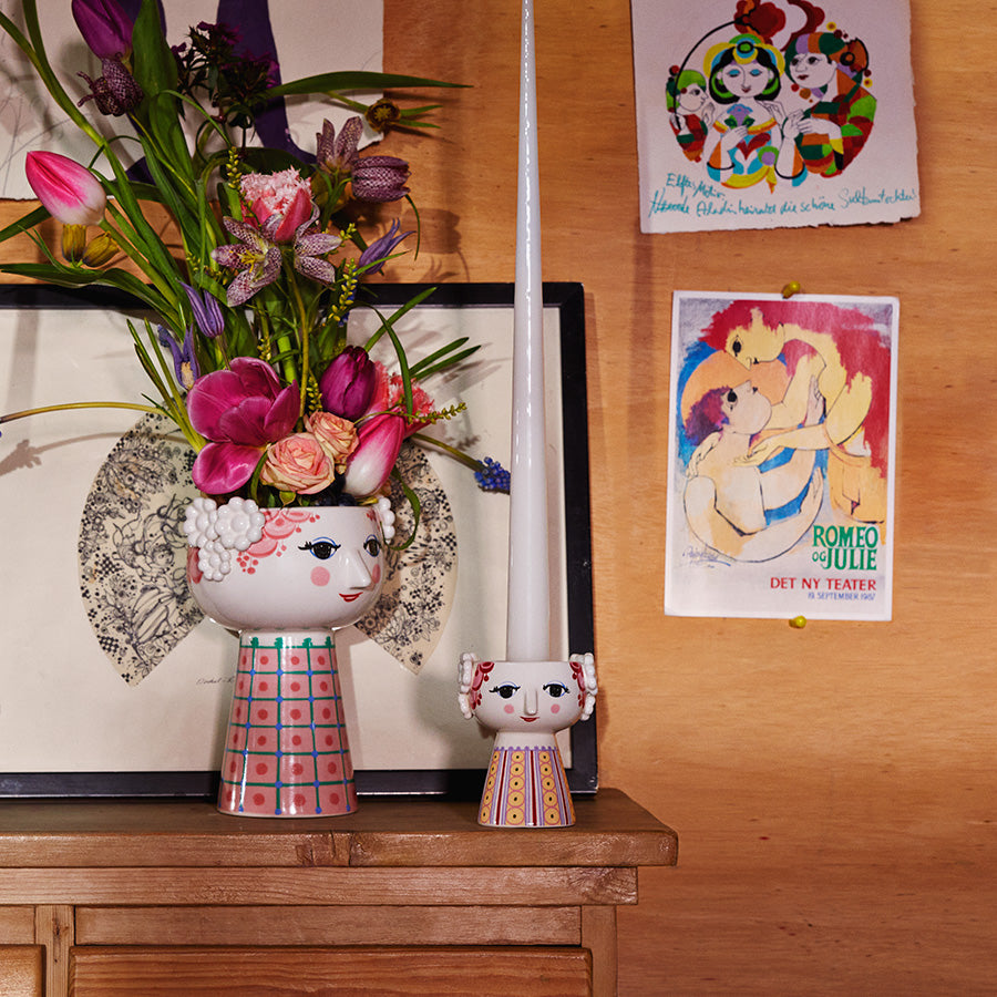 Bjørn Winblad Eva lysestake med blomsterarrangement, plassert i et koselig interiør med kunstplakater.