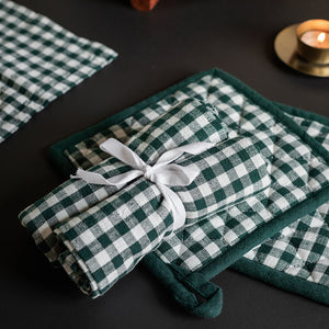 Settet med grytekluter og kjøkkenhåndklær i grønt rutemønster, elegant pakket med sløyfe. Ideelt for et stilrent kjøkken.