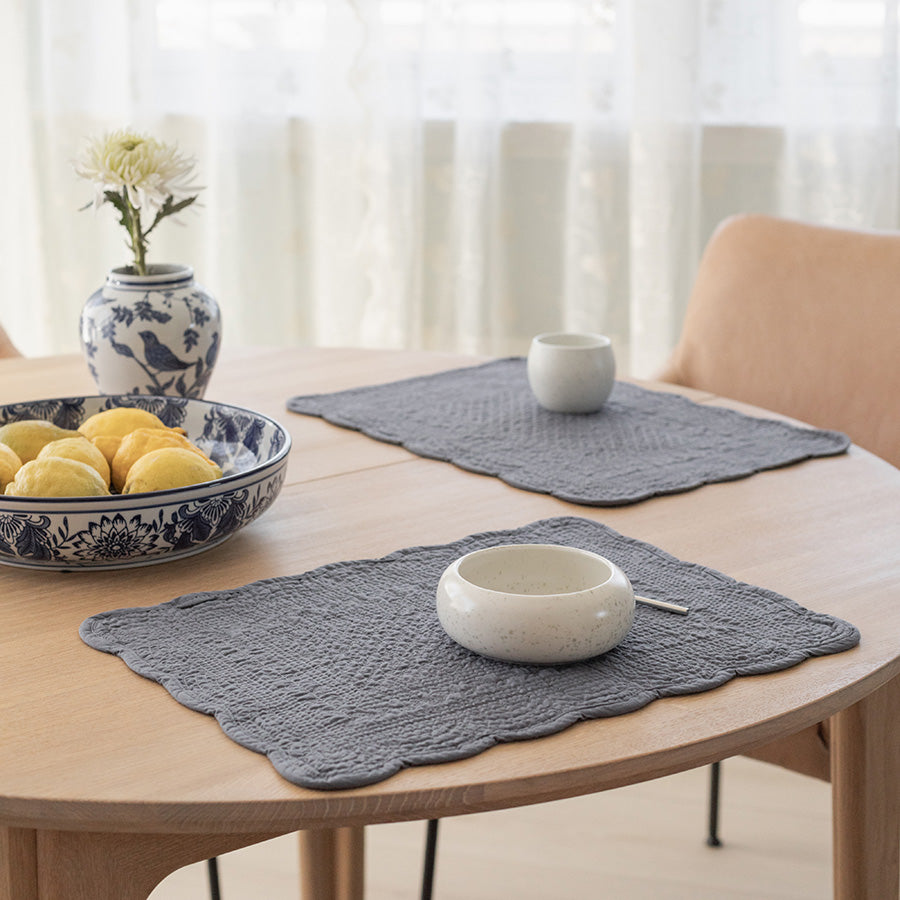 To blå dekkebrikker i quiltet bomull på et spisebord, stilrent design som gir bordet et elegant uttrykk