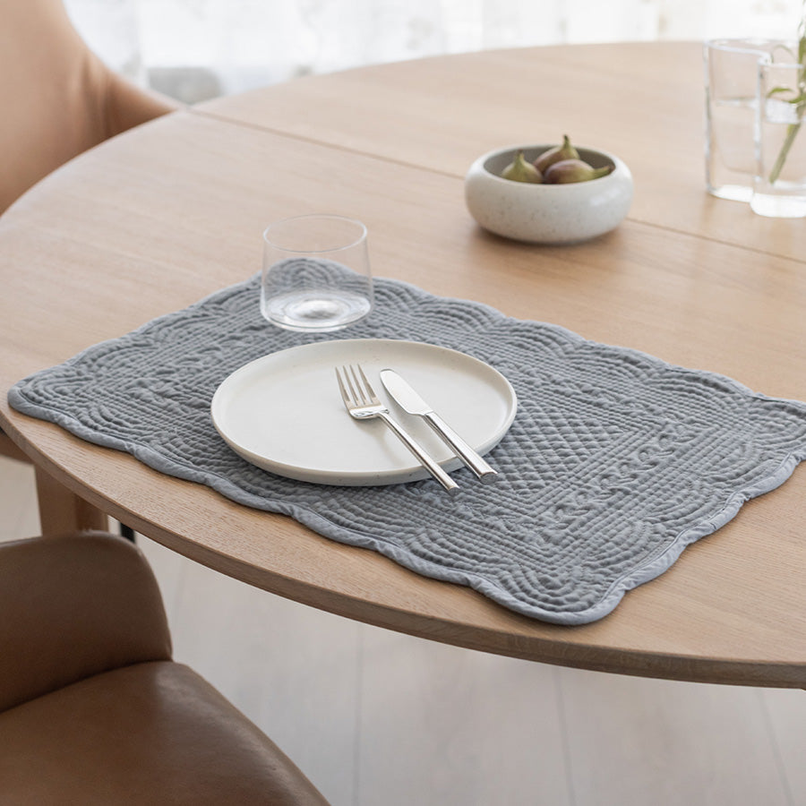 Stilig dekkebrikke laget av quiltet velour, presentert med et hvitt tallerken og bestikk, som gir et pent bordoppsett.