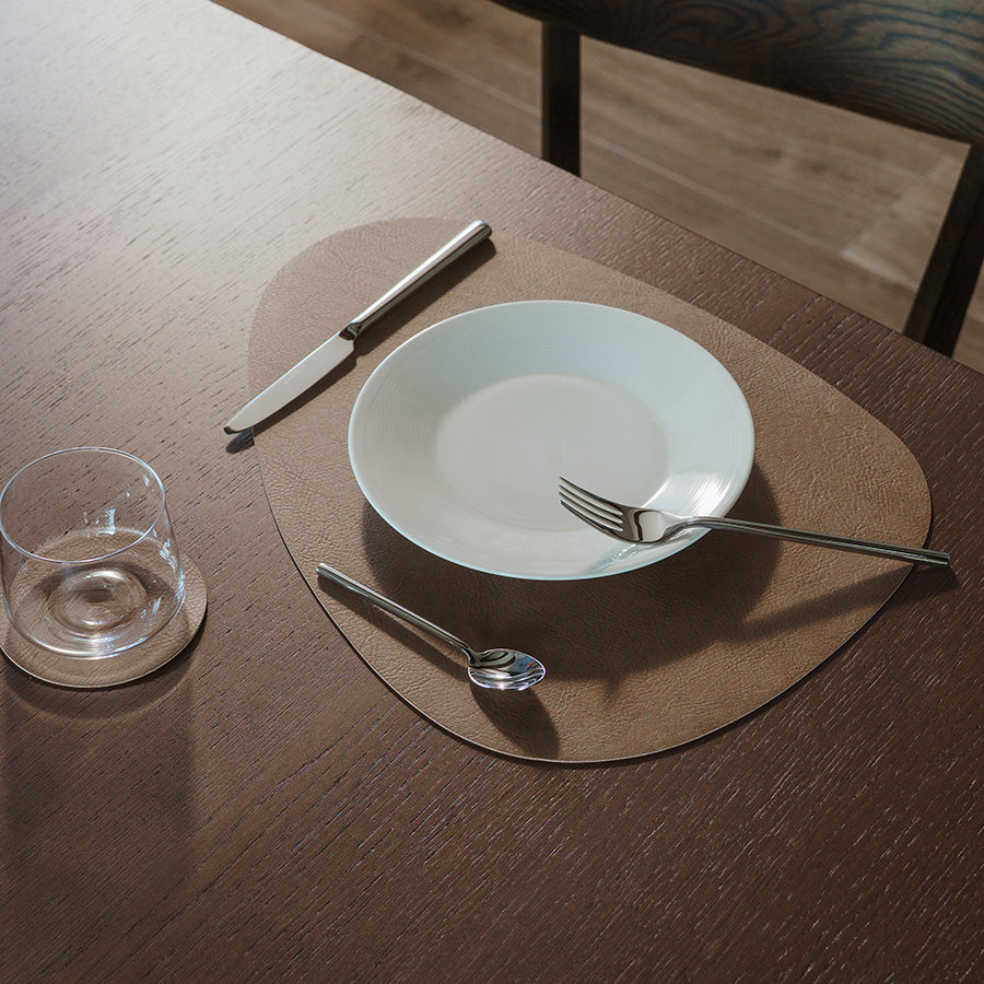 Spisebrikke på bord med tallerken, kniv og gaffel, viser harmonisk kombinasjon av design og funksjonalitet.