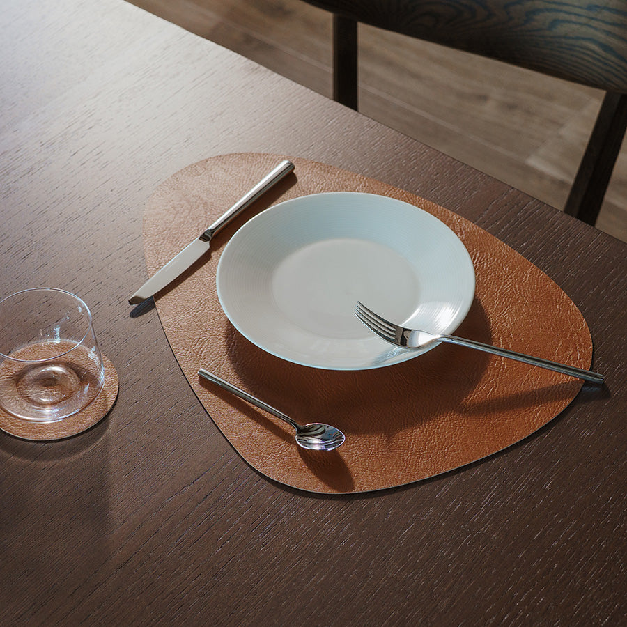 Komposisjon av spisebrikker i brune nyanser, dekorativt plassert på bord med tallerken og bestikk.