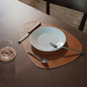 Komposisjon av spisebrikker i brune nyanser, dekorativt plassert på bord med tallerken og bestikk.
