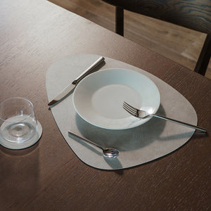 Borddekkingsbilde av spisebrikke i grå med tallerken og bestikk, perfekt for en elegant middag.