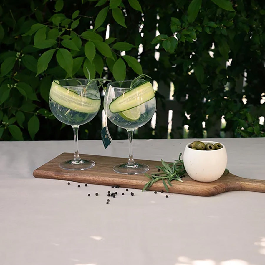 To spritzerglass med agurkskiver og en forfriskende cocktail, dekorert med urter, ideelt for uformelle samlinger.