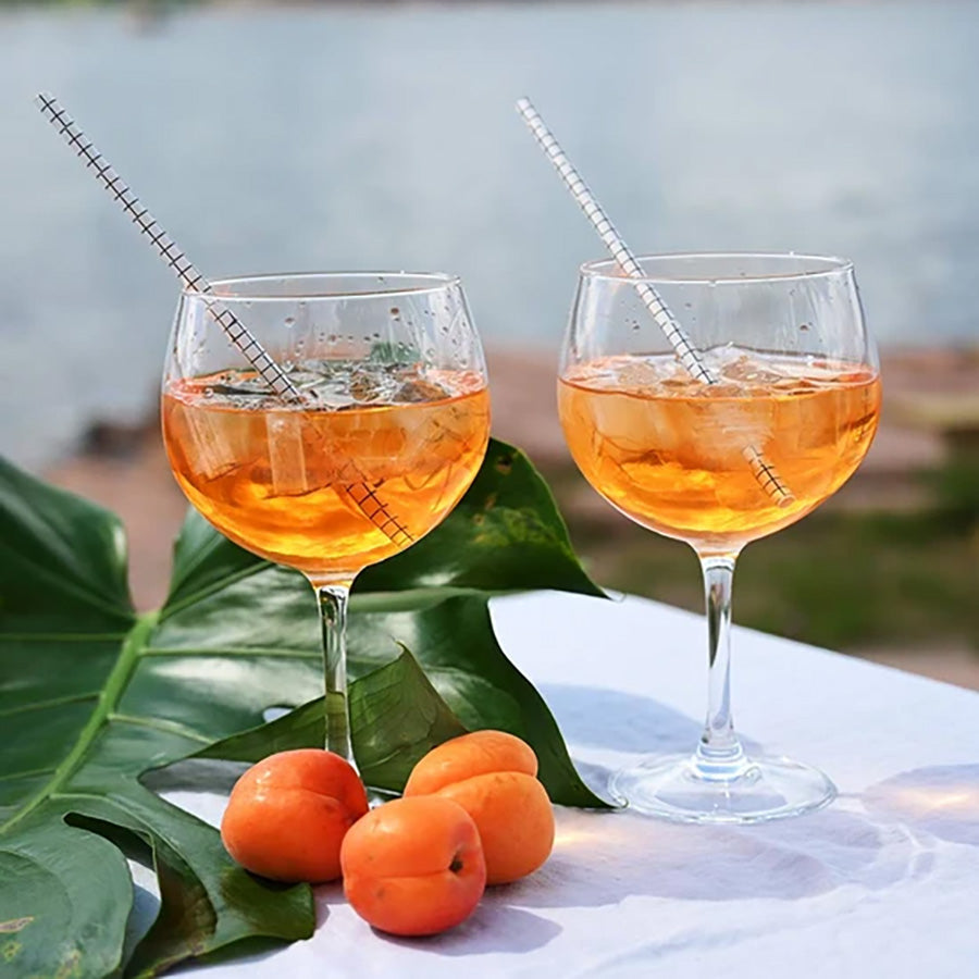 To spritzerglass fylt med forfriskende drinker, serveres ved en vakker utendørs setting med frukt og urter.