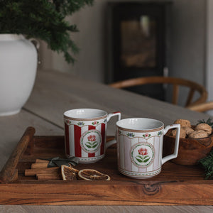 To Christmas Collection krus i rødt og rosa med stripemønster og blomstermotiv på trebord