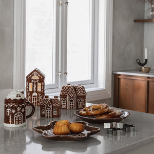 Pepperkakebrun tallerken med småkaker i et stemningsfullt julebord med pepperkakehus og julepynt