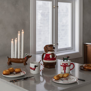Juledekorert kjøkken med keramisk dachshund lysestake, tente stearinlys, julekaker og festlige kopper