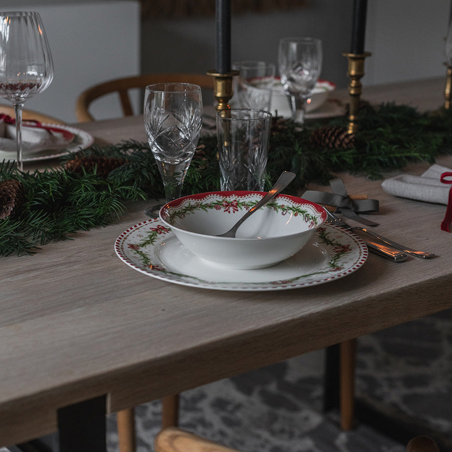 Juleglede skål på tallerken i elegant juleborddekking med bestikk, glass og juledekor