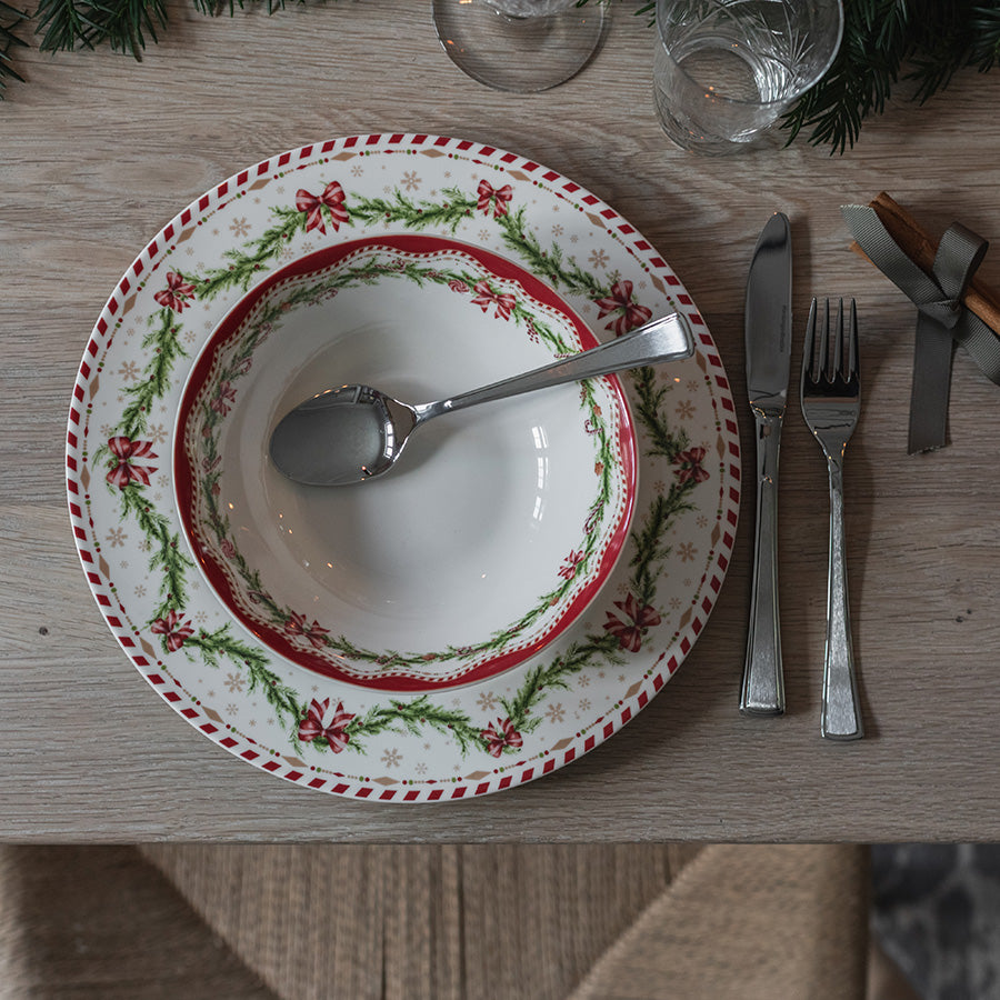 Juleglede skål på juledekket bord med matchende tallerken, bestikk og julepynt
