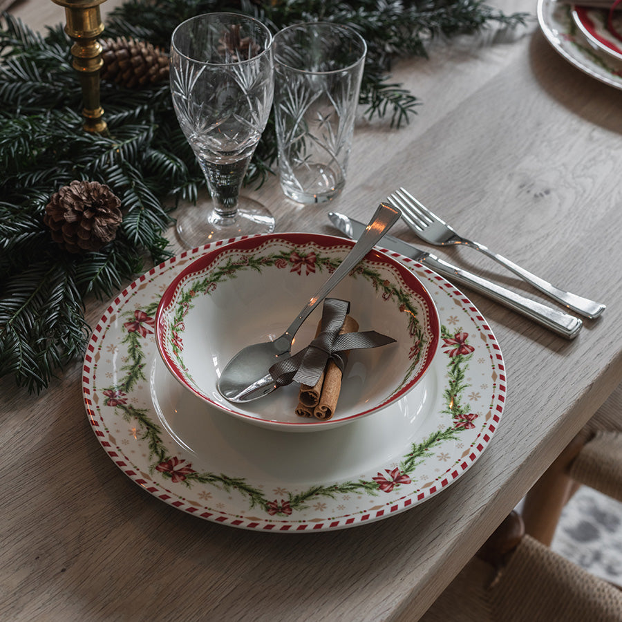 Dekorativ Juleglede skål med skje på festlig julebord med servise, glass og granbar
