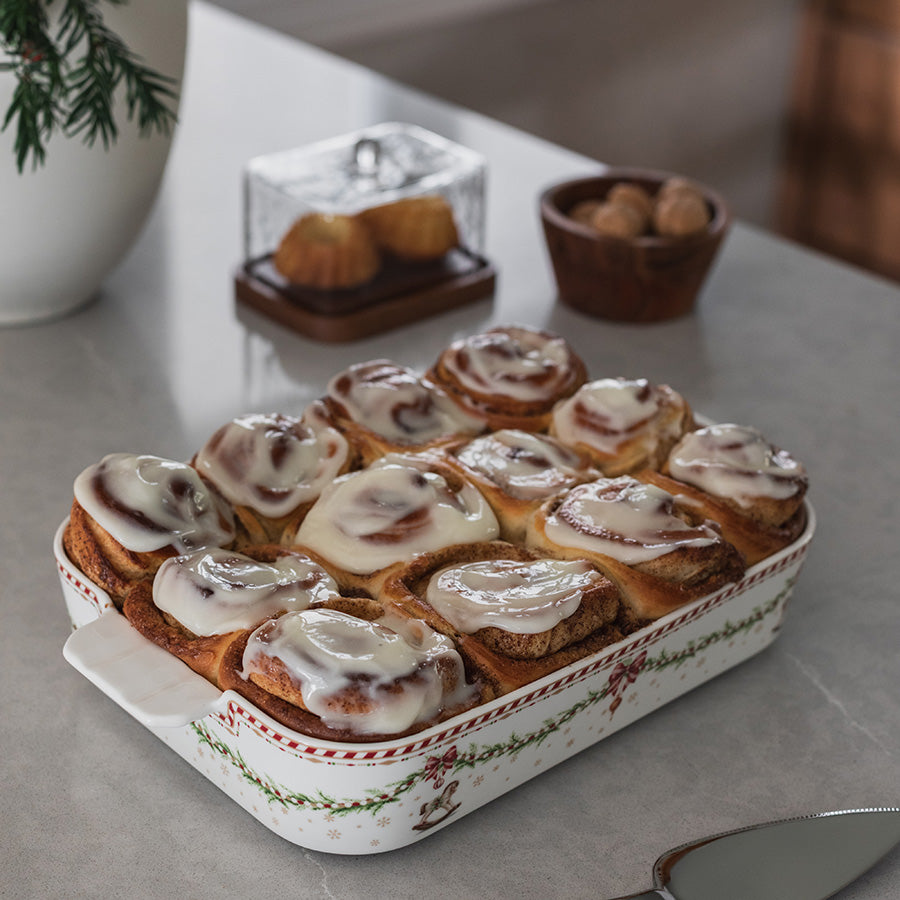 Ildfast form med juledekor fylt med nystekte kanelsnurrer med glasur, klar til servering