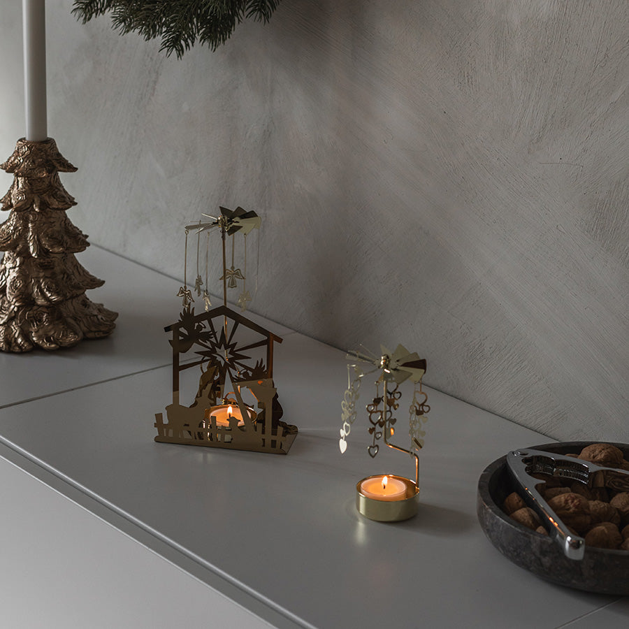 Englespill med julekrybbe i gull og tent telys, elegant juledekor på skjenk
