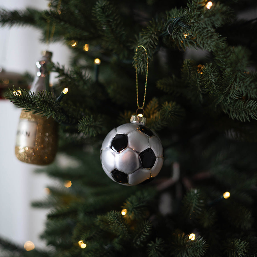 Julekule i glass med fotballdesign henger på et pyntet juletre