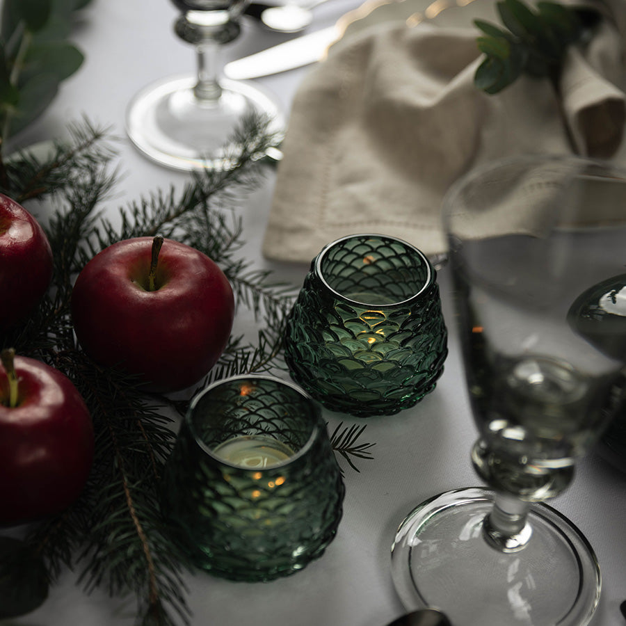Mørkegrønne Furu telysholdere med lys blant epler og furugrener på julebordet