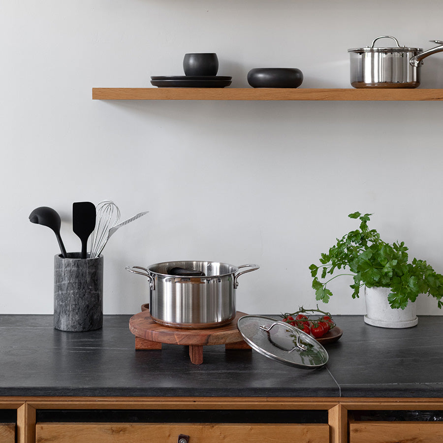 Moderne kjøkkeninnredning med en gryteskje fra Classicpro, grytelokk og serveringsfat på en treplate.