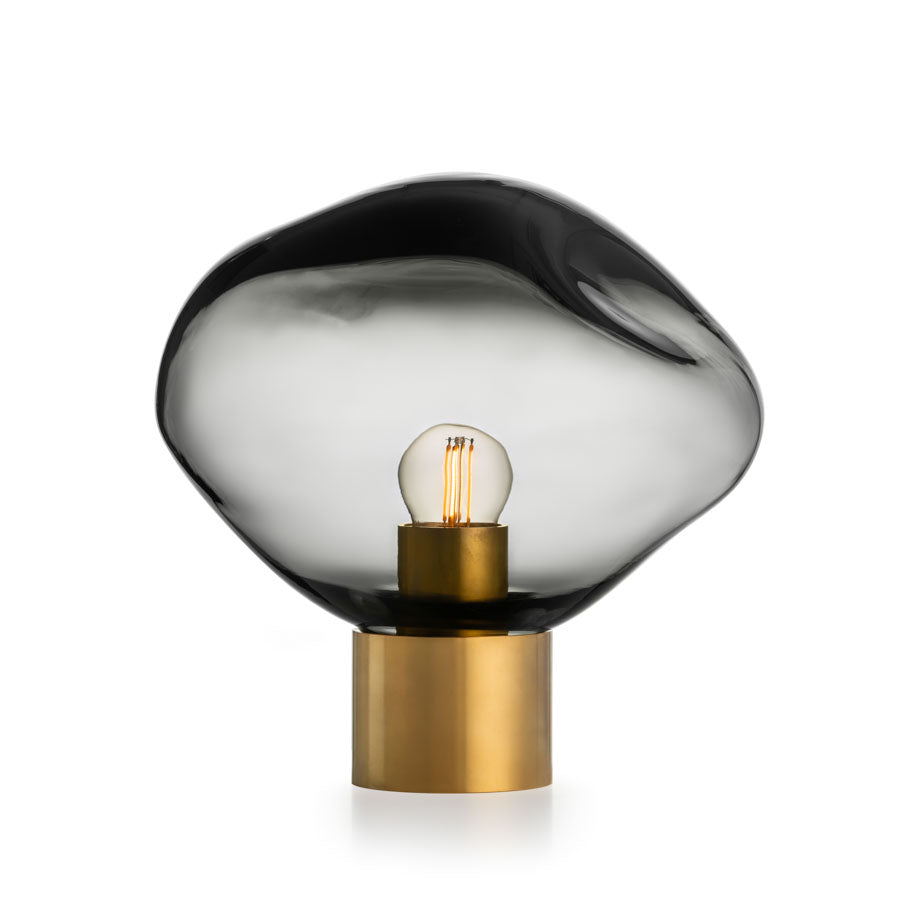 Elegant bordlampe fra Hadeland Glassverk, Crystal Stone i lys røkgrå, med en unik håndblåst kuppel, perfekt for å skape en sofistikert atmosfære i stuen eller soverommet.