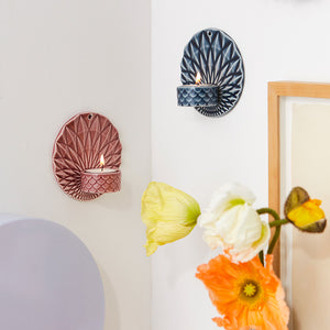 To vegghengte telysholdere i forskjellige farger, inkludert rosa, montert på vegg med lys i, ideelt til dekor i moderne hjem.