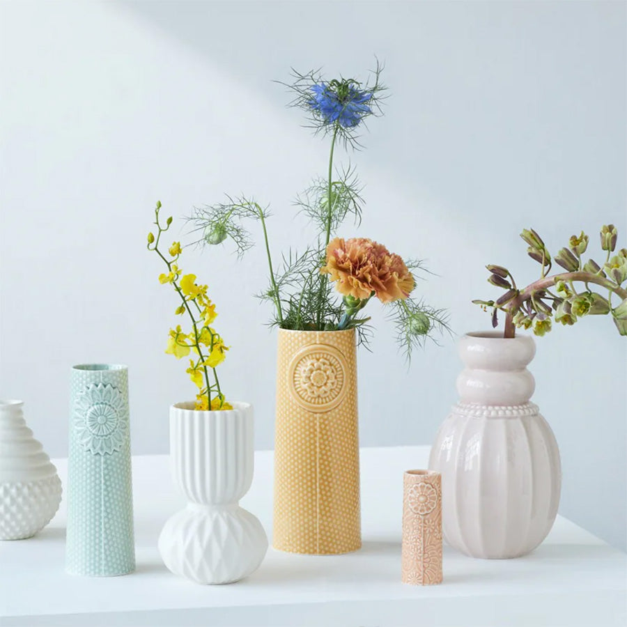 Samling av forskjellige vaser i pastellfarger inkludert Pipanella Dot vase i curry, fylt med blomster, ideell for moderne innredning.