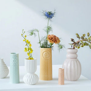 Samling av forskjellige vaser i pastellfarger inkludert Pipanella Dot vase i curry, fylt med blomster, ideell for moderne innredning.